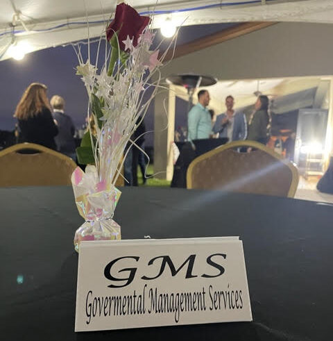 A name card with GMS at a table featuring a rose.